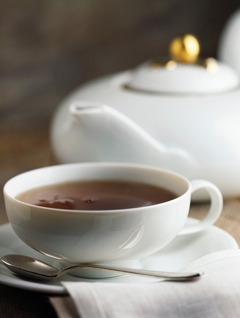 Eine Tasse mit Teekanne im Hintergrund