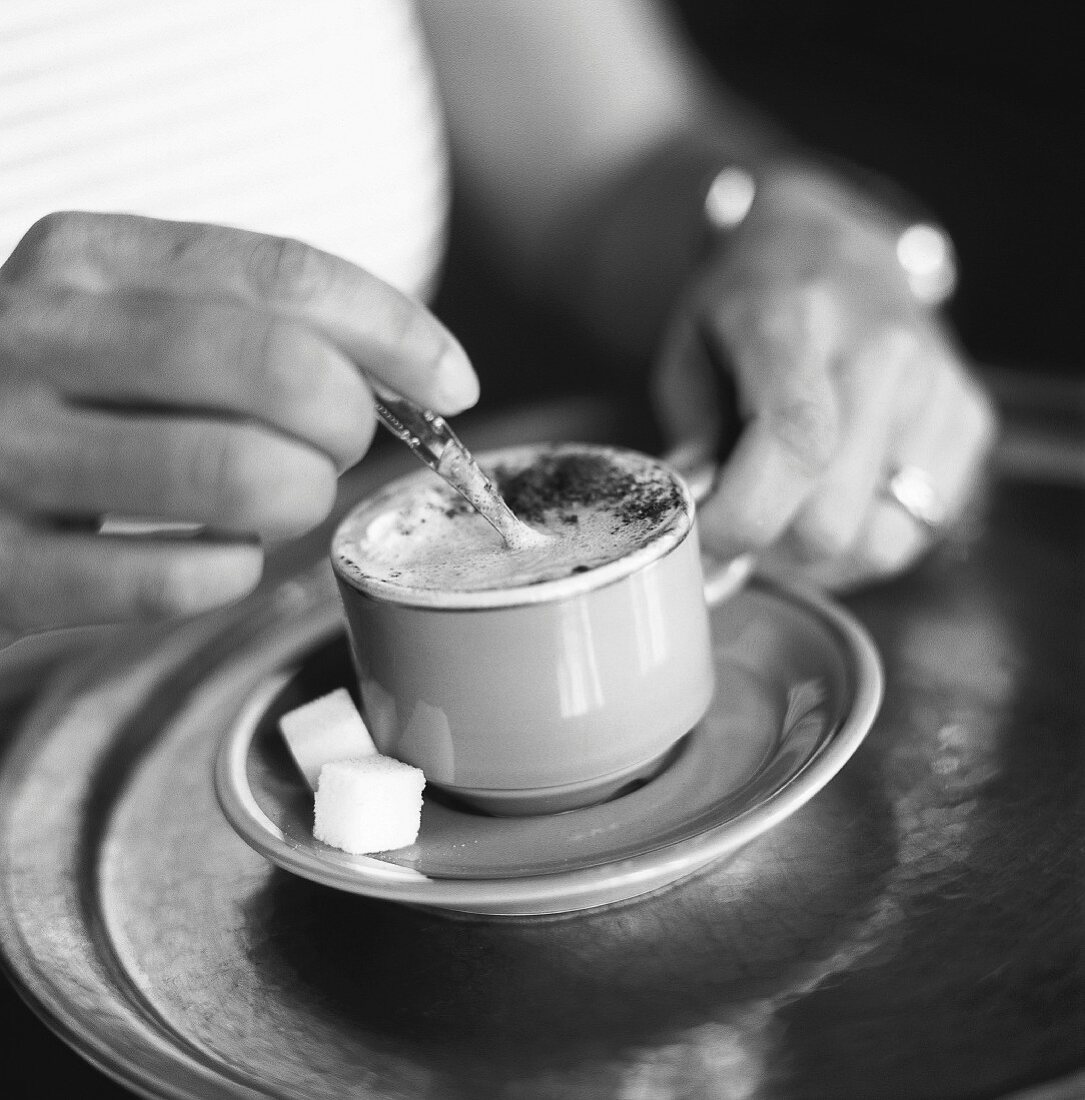 person stirring cappuccino