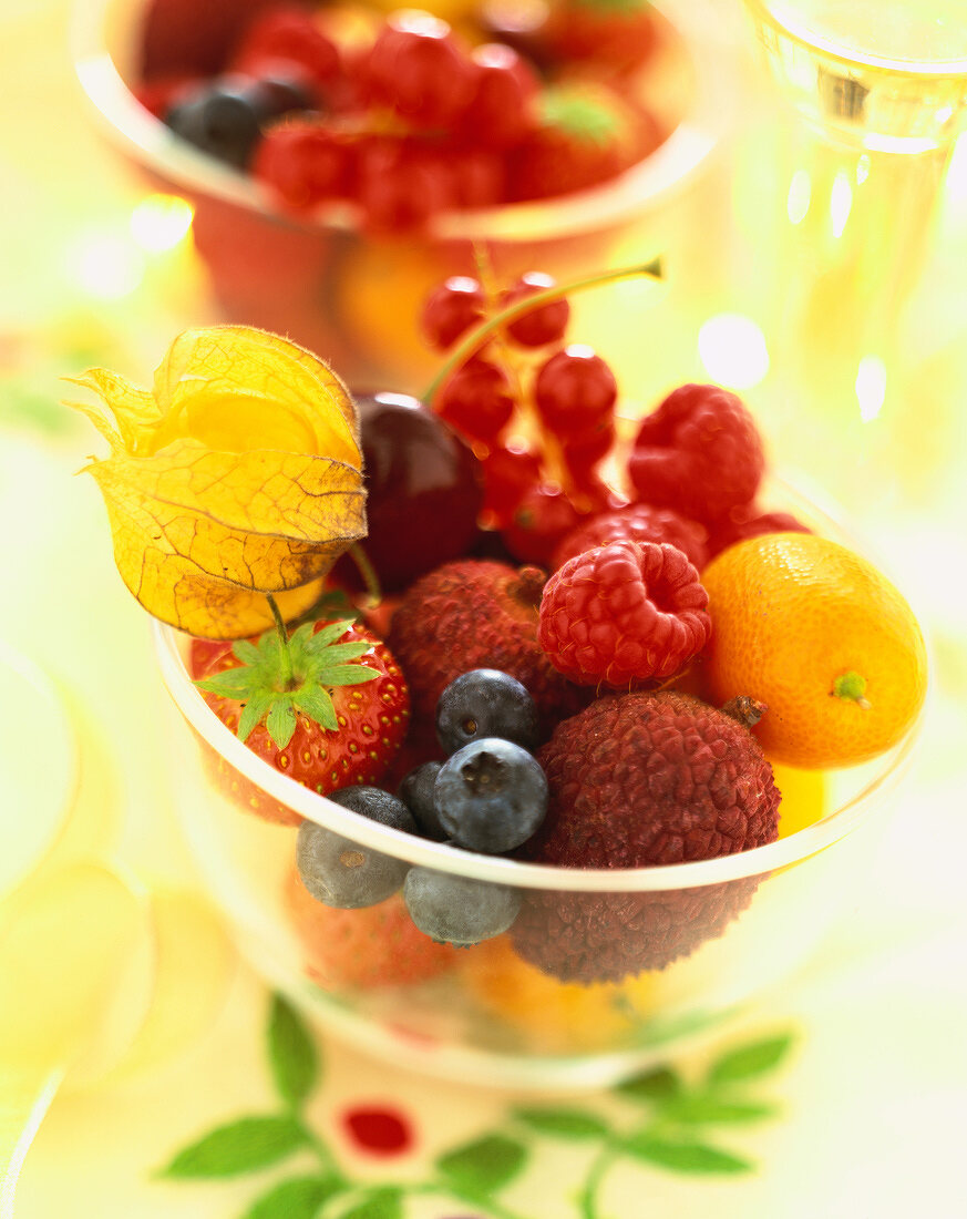 Eine Schale mit frischem Obst (Beeren, Litschis, Physalis, Kumquats)