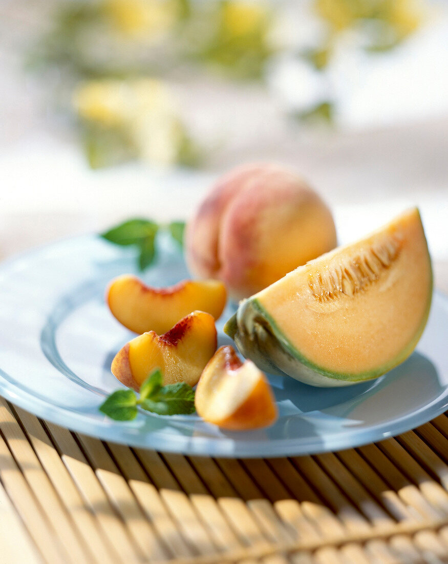 Melonenstück und Pfirsichstücke auf Teller im Freien