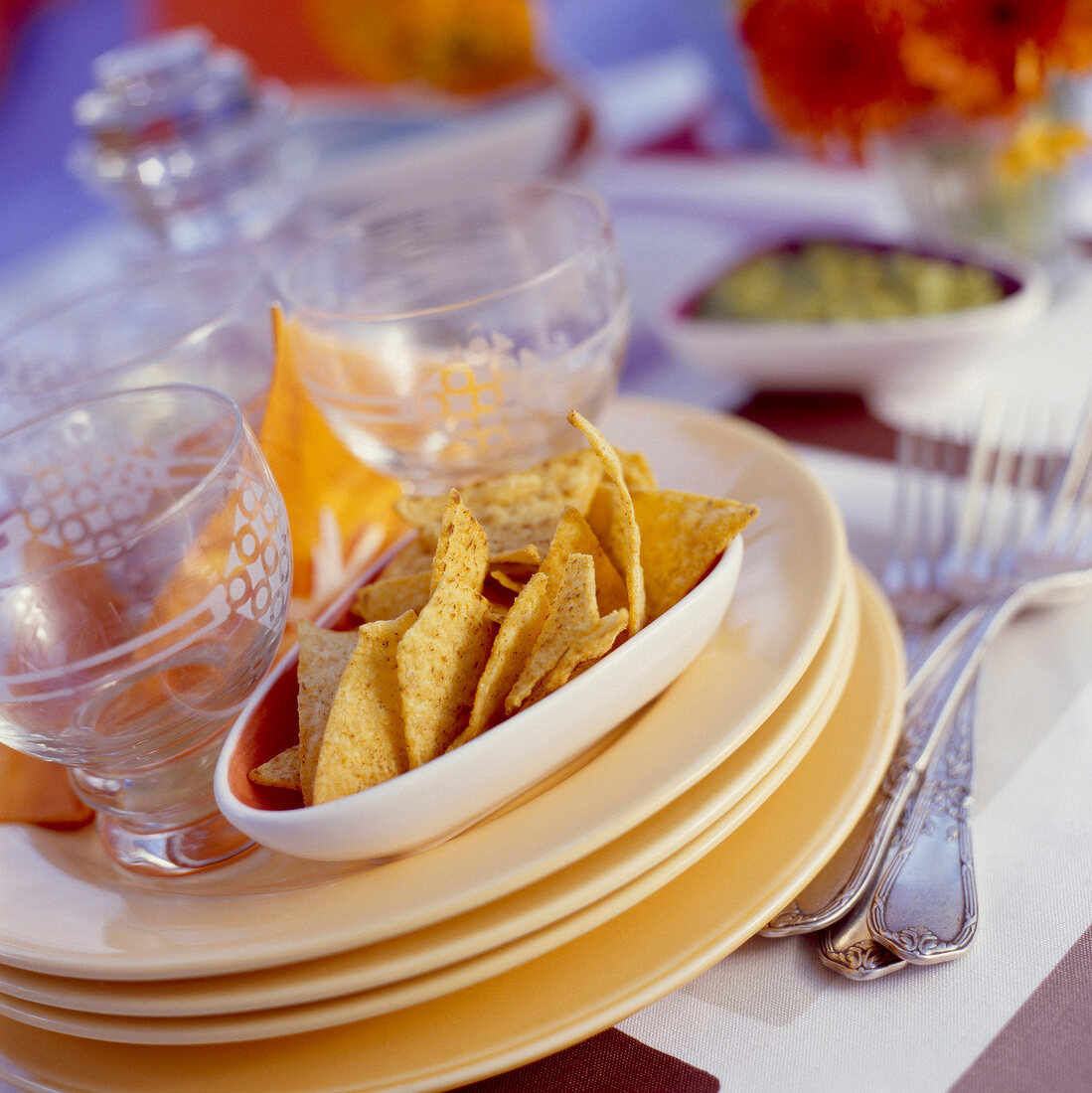 Tellerstapel mit Gläsern und Tortillachips