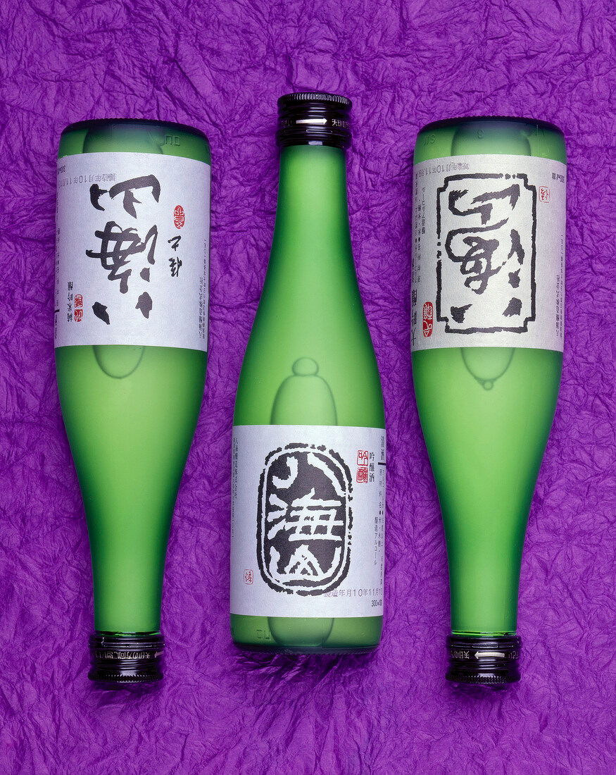 Drei Flaschen Sake auf violettem Untergrund