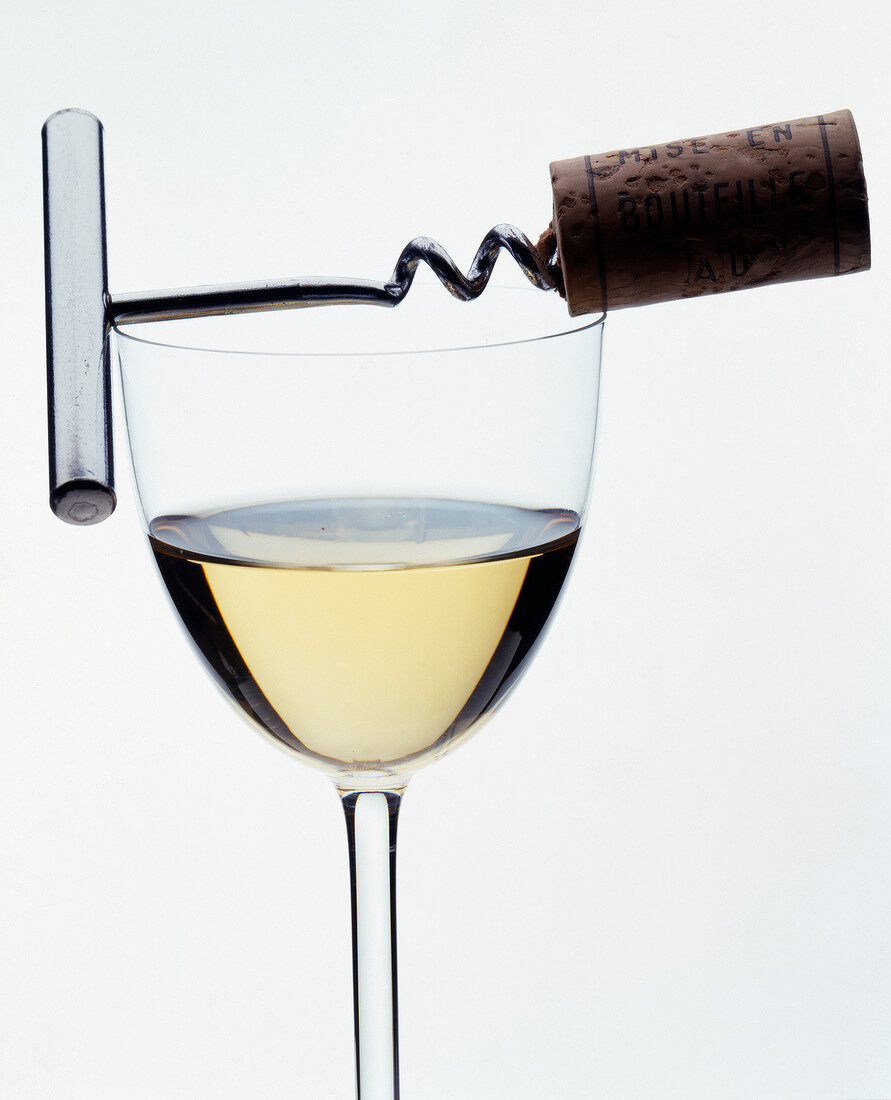 Ein Glas Weißwein mit Korkenzieher vor weißem Hintergrund