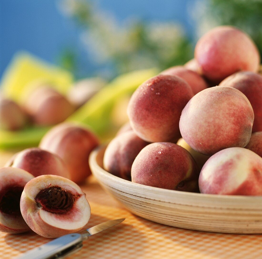 Frische Pfirsiche in Schale und auf Tischtuch