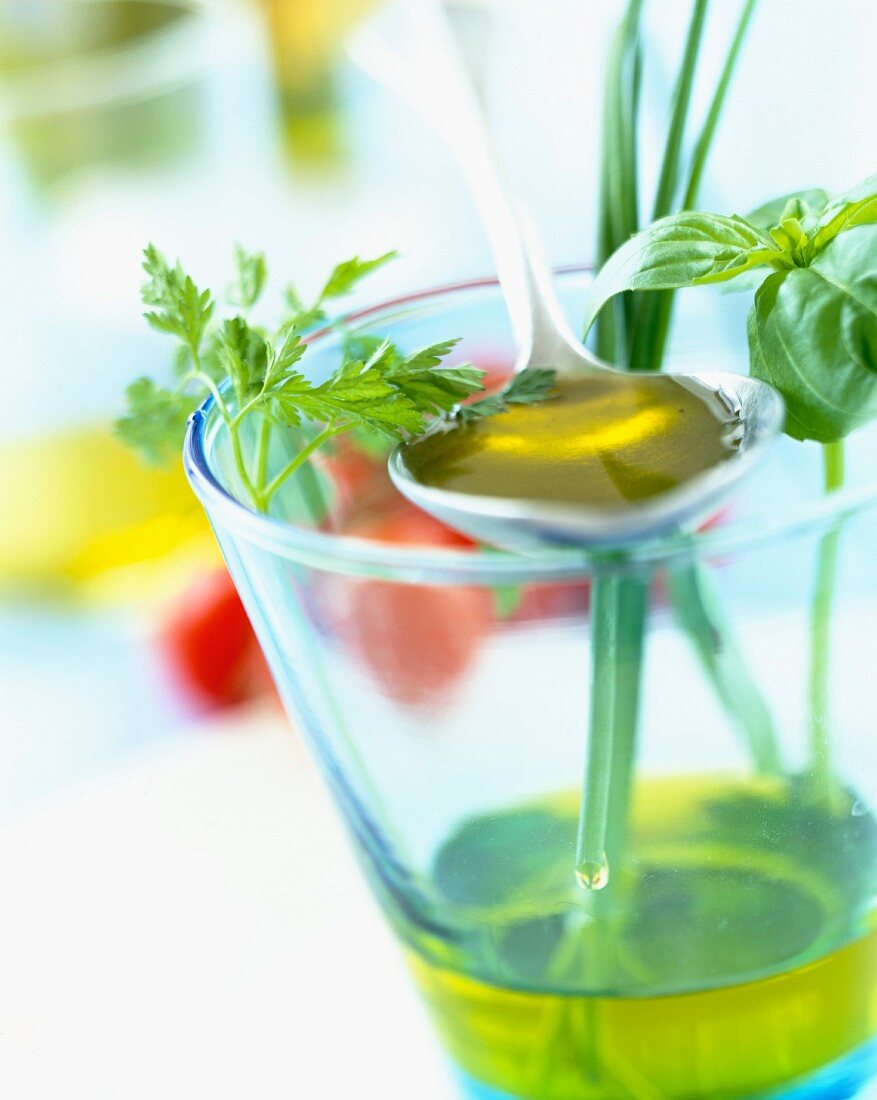 Glass of olive oil with fresh herbs