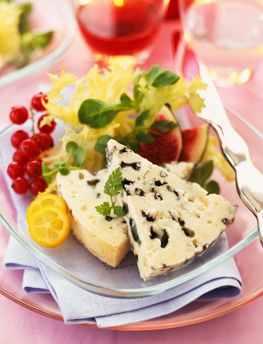Zwei Stücke Roquefort auf Teller mit Salat- und Obstgarnitur