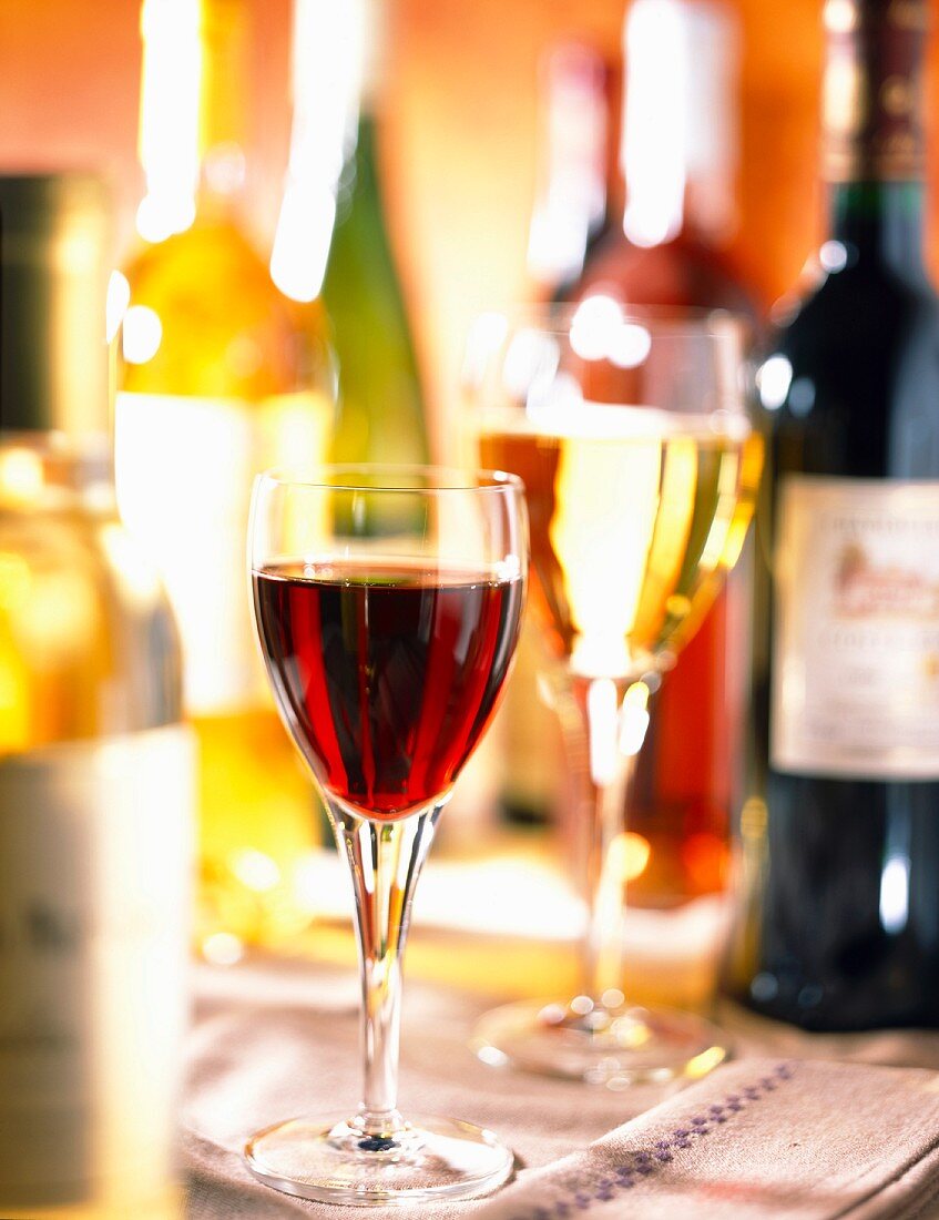 Flaschen und Gläser mit Weißwein und Rotwein