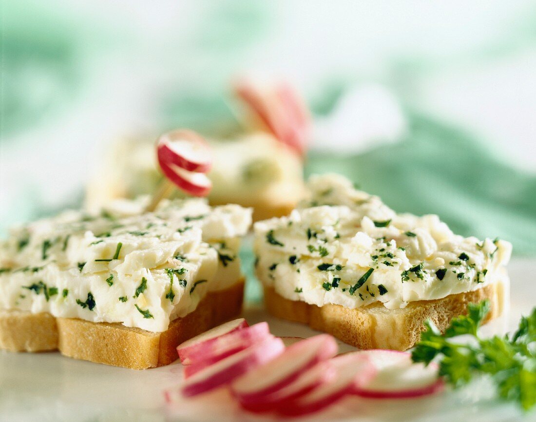 Frischkäse mit Kräutern auf Toastbrot und Radieschen