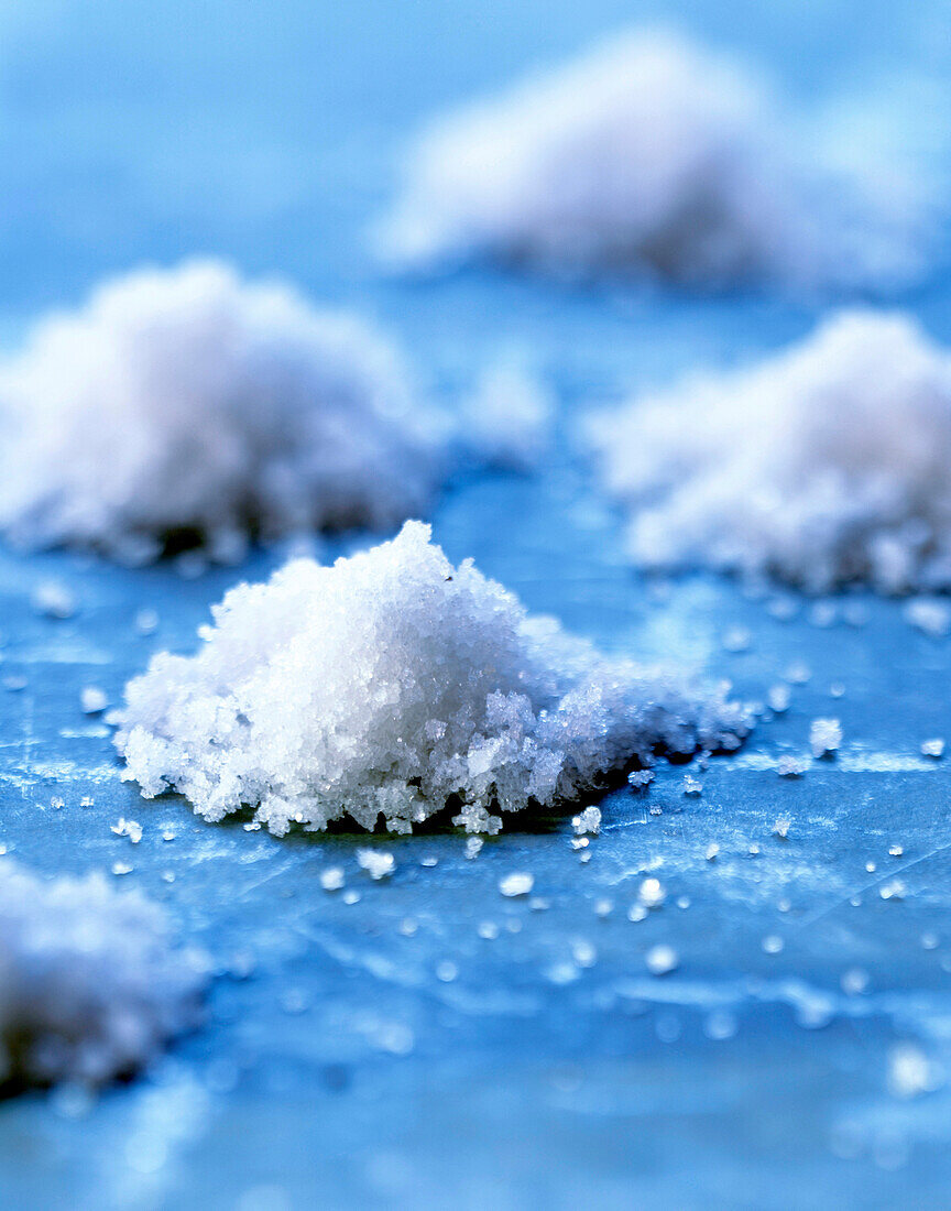 Kleine Häufchen grobes Meersalz auf blauem Untergrund