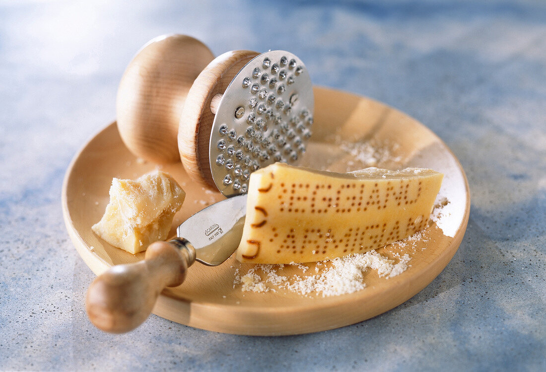 Parmesan mit Parmesanmesser auf einem Holzteller