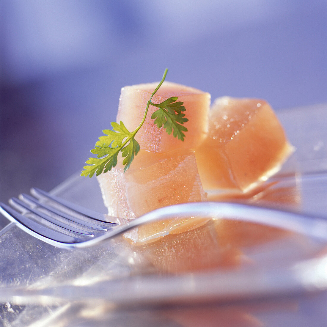 Rohe Fischwürfel mit Gabel auf einem Glasteller