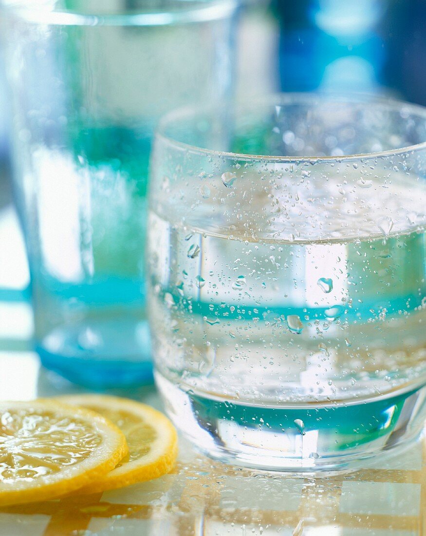 Ein Glas Wasser, daneben Zitronenscheiben