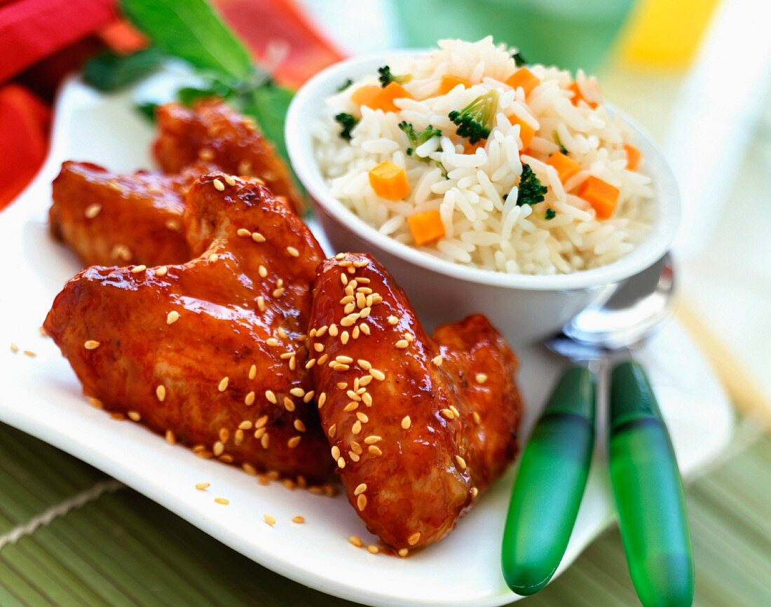 Glazed chicken wings with sesame seeds and bowl of rice