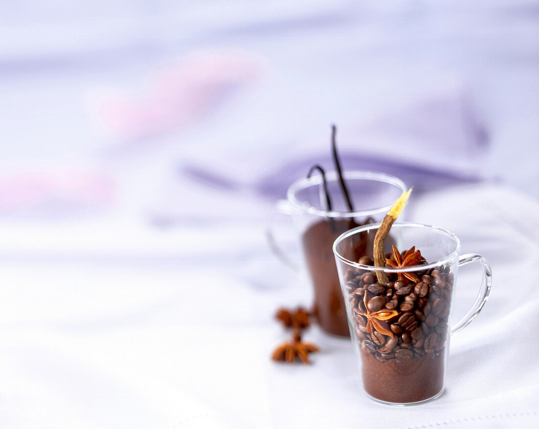 Kaffeepulver, Kaffeebohnen, Sternanis, Vanilleschote zum Aromatisieren von Kaffee in Gläsern