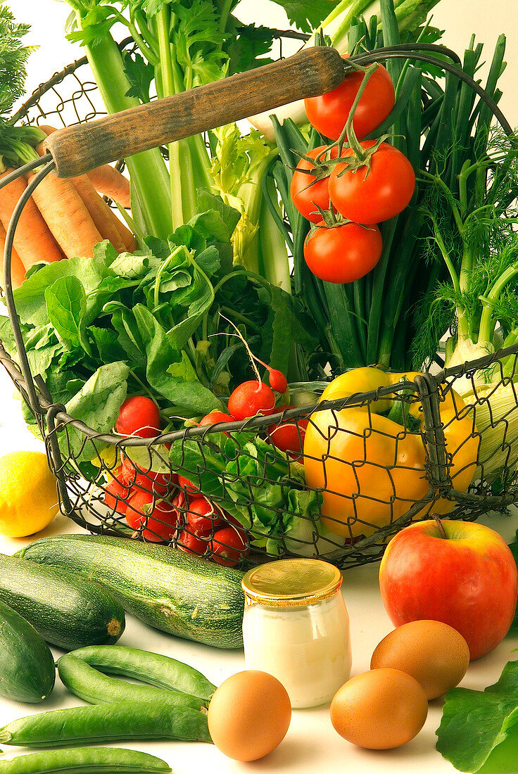 Stillleben mit frischem Gemüse im Korb, Eiern und Joghurtglas