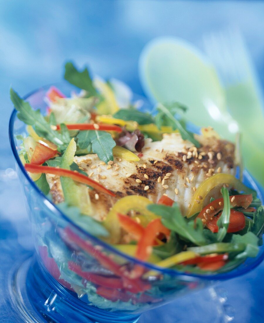 Warm fish salad with peppers, sesame seeds and tomato