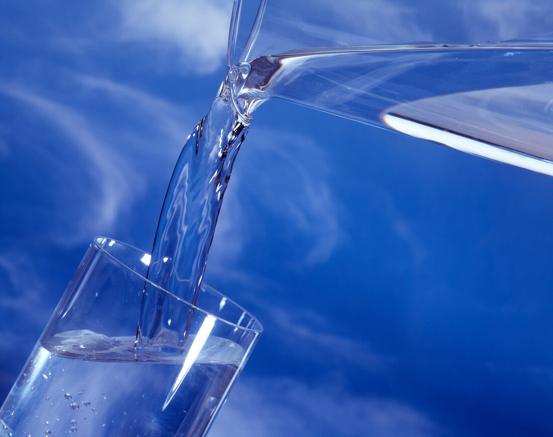 Wasser aus einer Kanne in ein Glas gießen