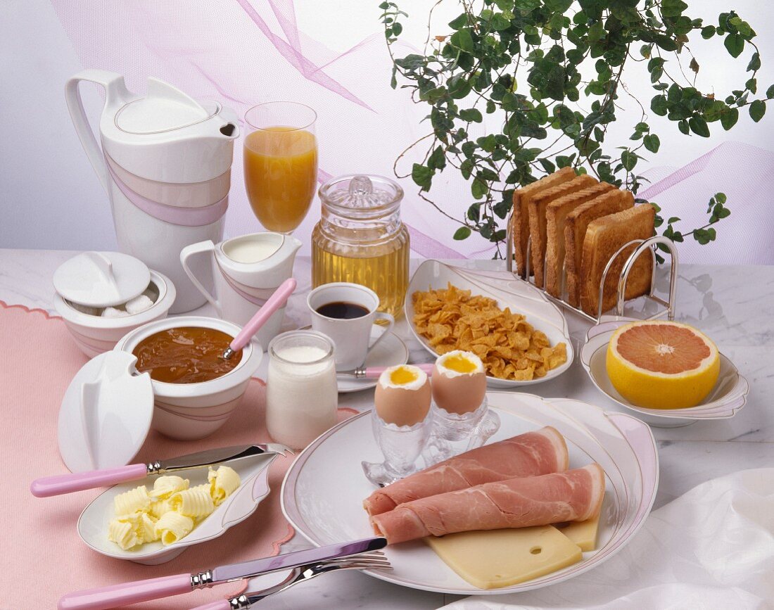 Grosses Frühstück mit Konfitüre, Butter, Schinken, Käse, weichen Eiern, Cerealien, Toast usw.
