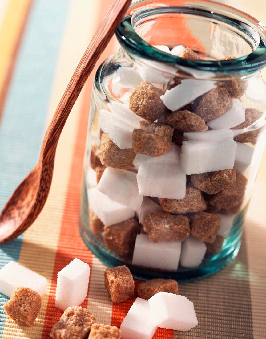 Brown and white sugar lumps in jar