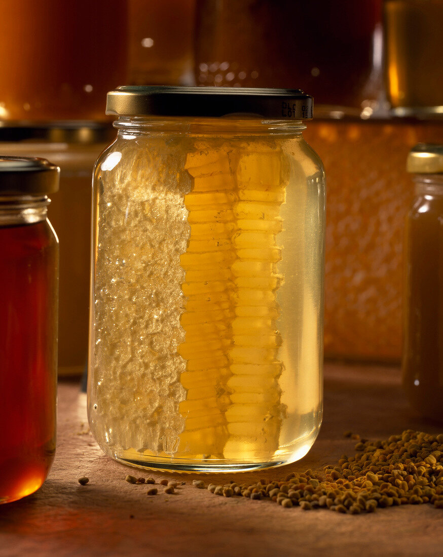 jar of honey with honeycomb in ray of sunlight