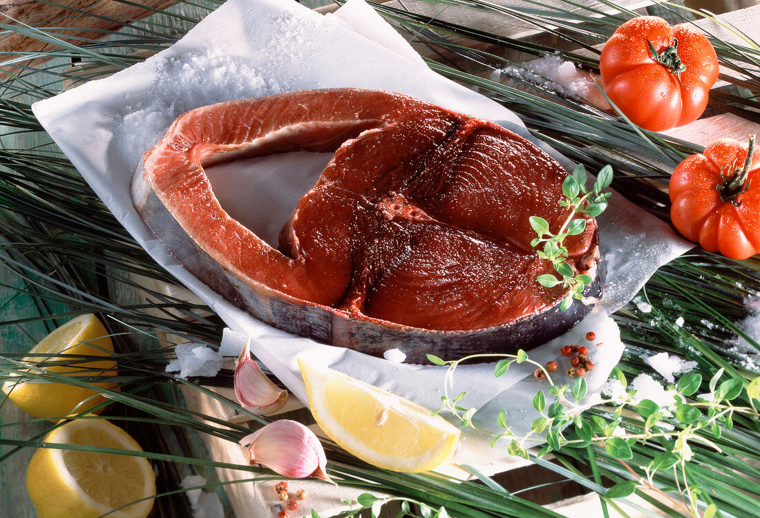 Zutatenstillleben: Thunfischkotelett auf Papier, Gemüse, Kräuter und Gewürze