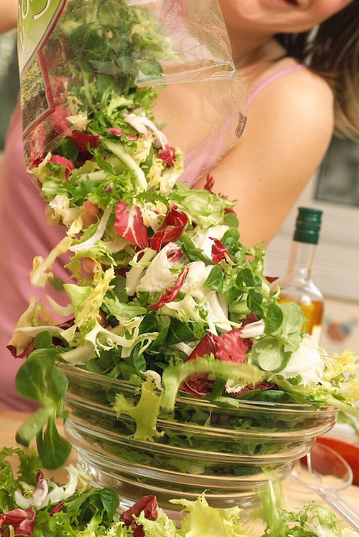 Gemischten Salat aus einer Plastiktüte in eine Salatschüssel geben