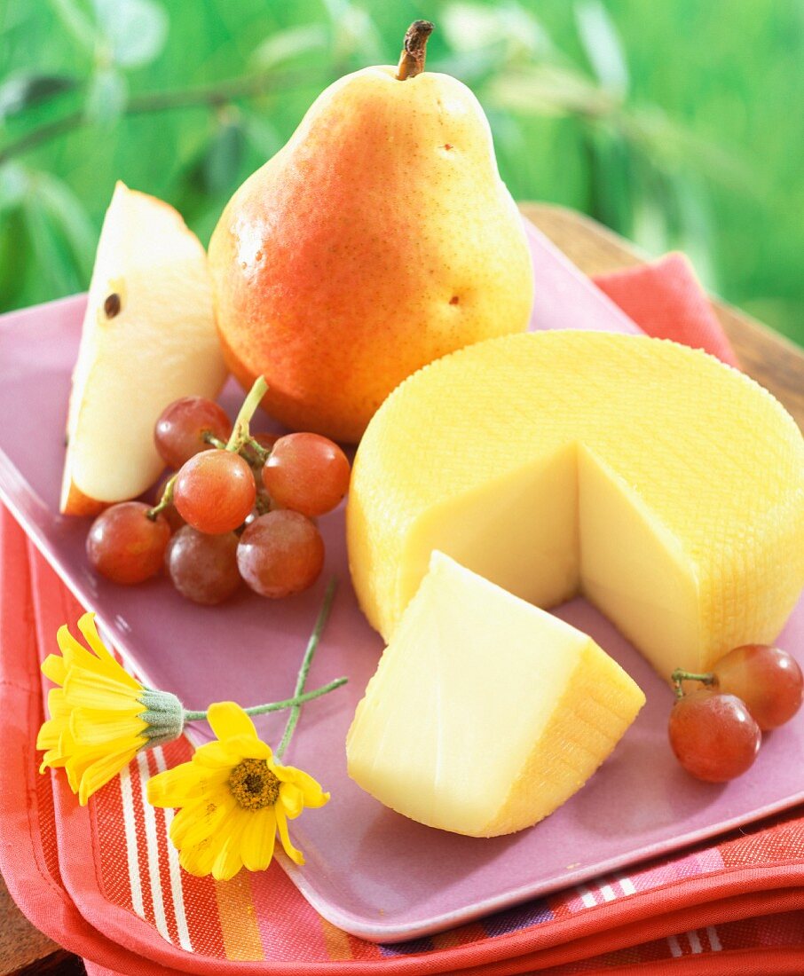 Port-Salut-Käse auf Tablett mit Trauben und Birne