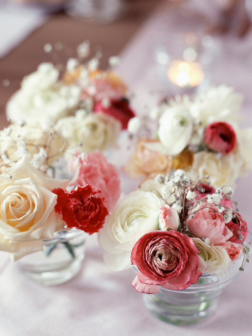 Vier Gläser mit bunten Rosen auf dem Tisch