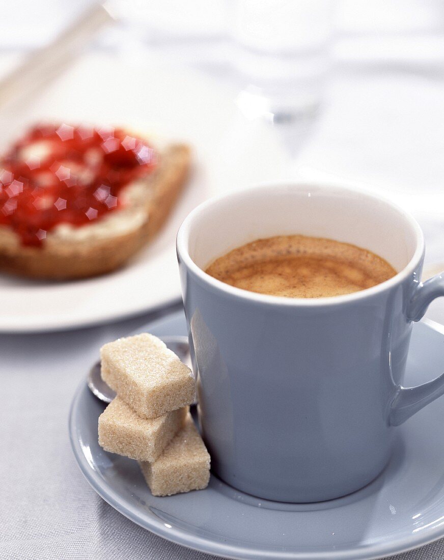 Tasse Kaffee mit Würfelzucker und Marmeladenbrot
