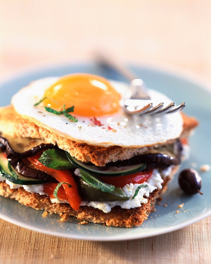Toasted sandwich with fried egg, vegetables and goat's cheese