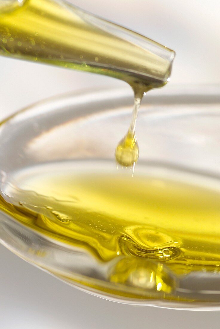 Von einem Kännchen Olivenöl auf einen Löffel träufeln