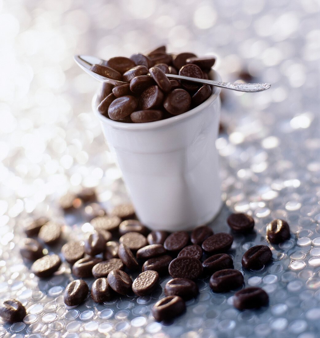 Schoko-Kaffeebohnen mit Becher und Löffel