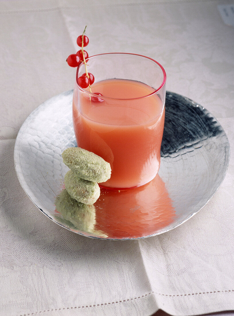 Grapefruit-Johannisbeer-Saft im Glas auf silberner Schale