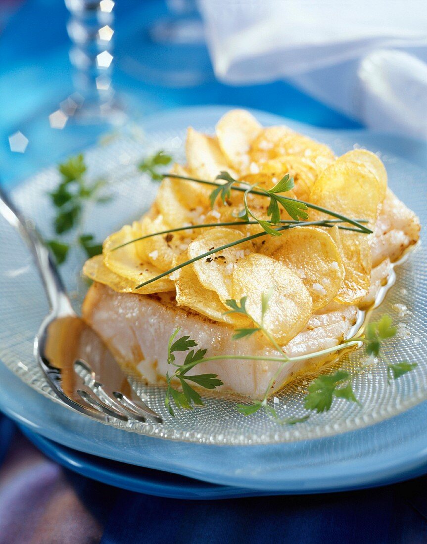 Piece of cod covered with thin slices of potatoes