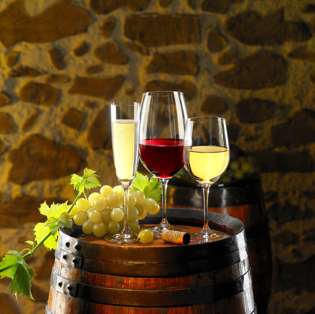 Sekt, Rotwein und Weißwein in Gläsern auf Weinfass