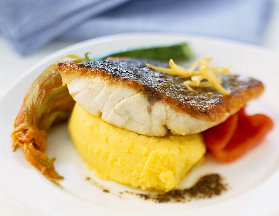 Piece of grilled bass with mashed potatoes and courgette flower