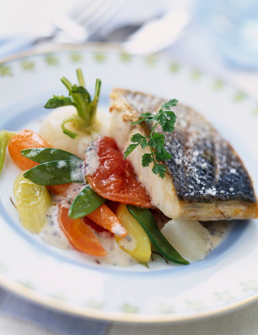Grilled piece of bass with granulated salt and young vegetables