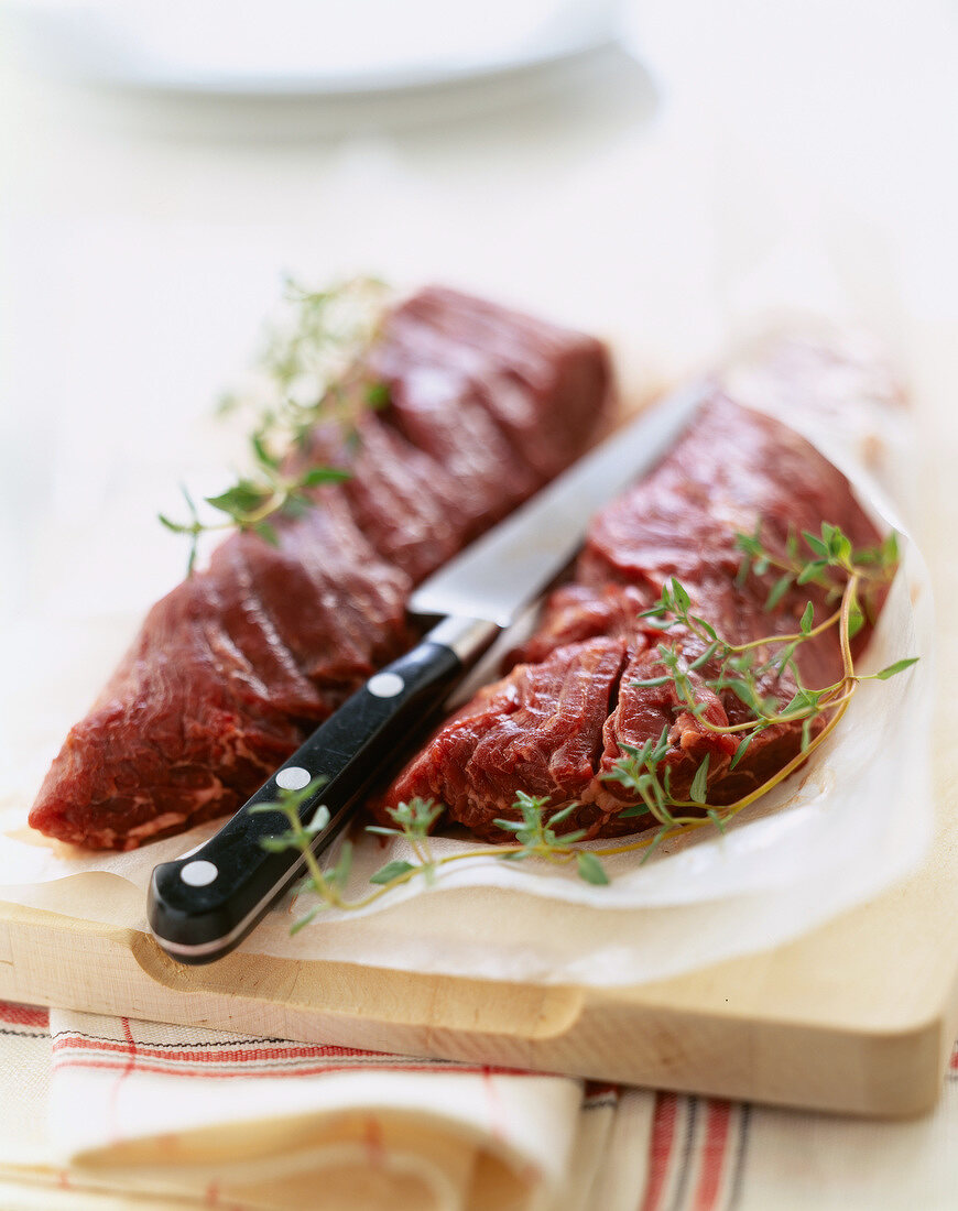 Eingeschnittene Lendensteaks vom Rind mit Thymian auf Schneidebrett