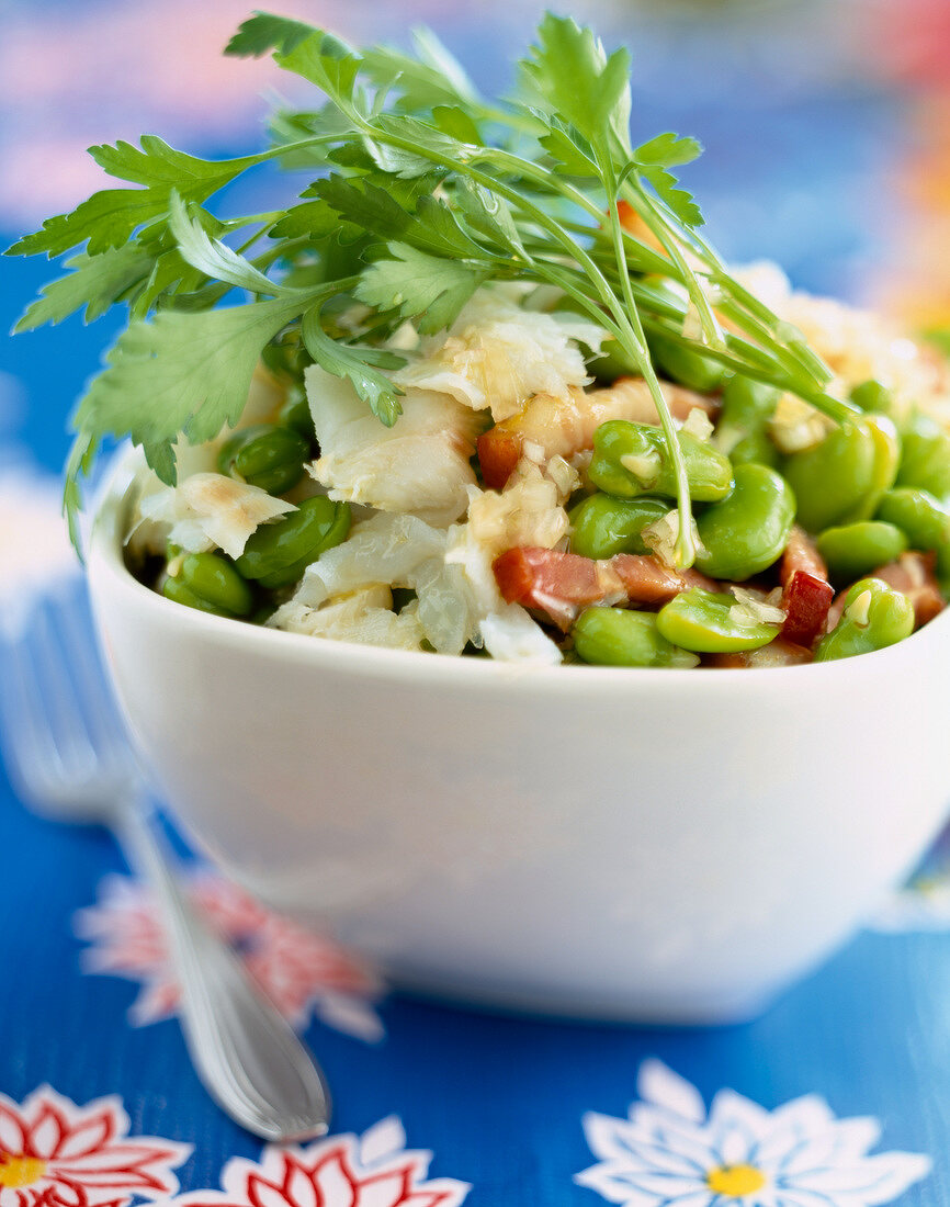 Salat mit Kabeljau, Bohnen, Speck und Petersilie in einer Schale