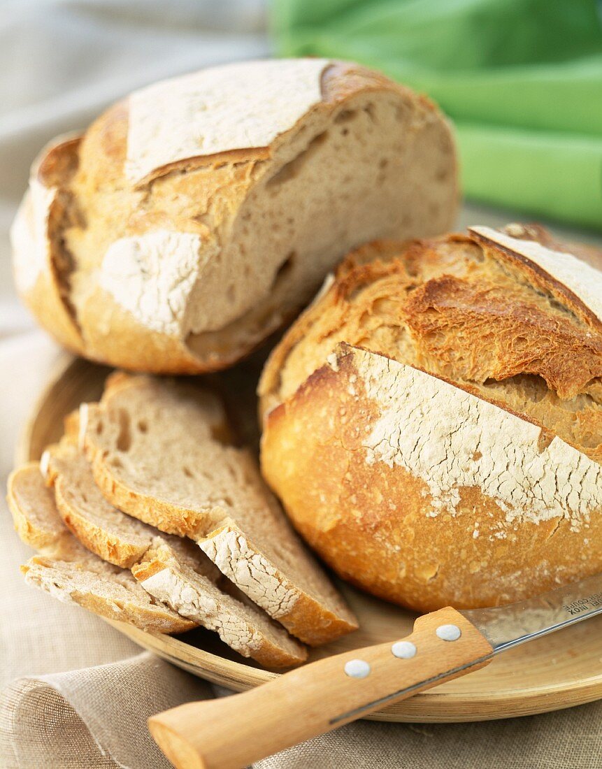 Angeschnittenes Landbrot mit Messer auf Holzteller