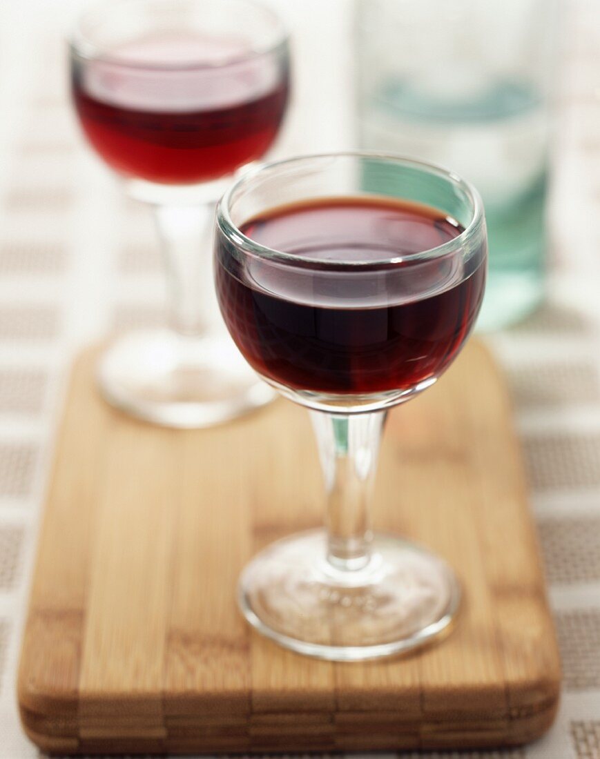Zwei Gläser Rotwein auf Holzbrett