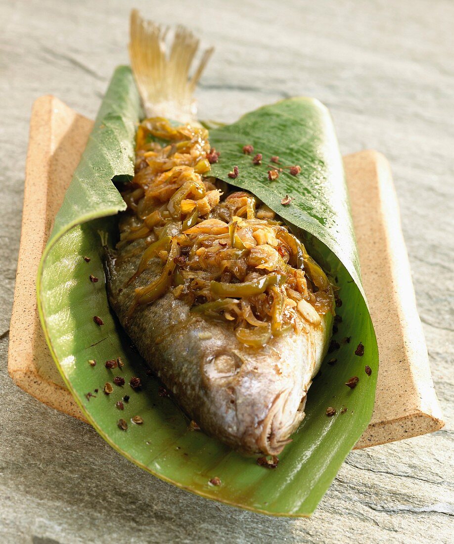 Sea bream in banana leaf with onions and green pepper