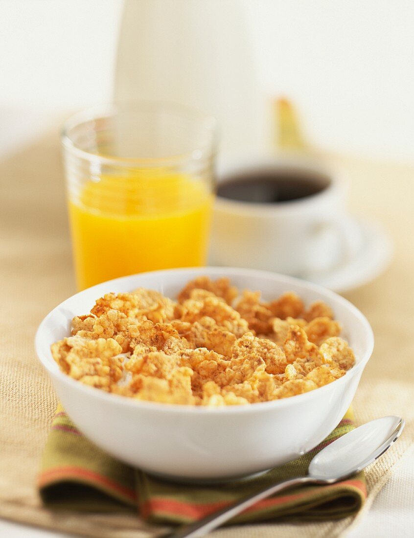 Ein Schälchen mit Cornflakes, dazu Orangensaft und Kaffee