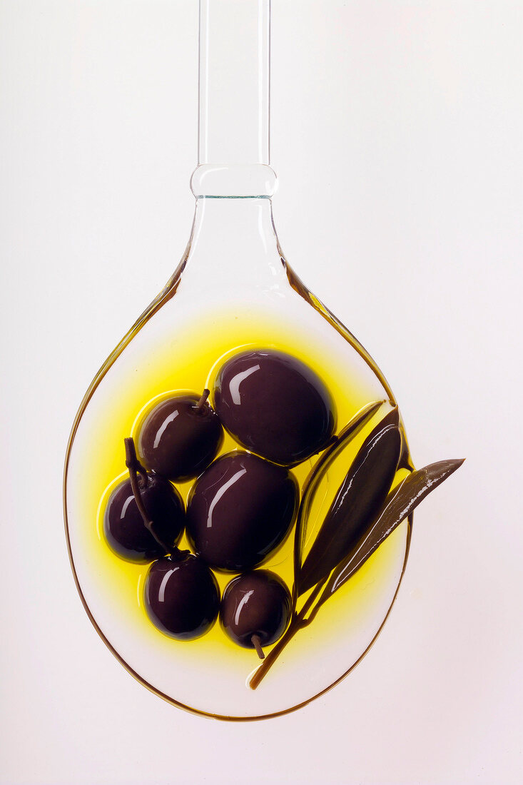 Schwarze Oliven auf Löffel in Olivenöl