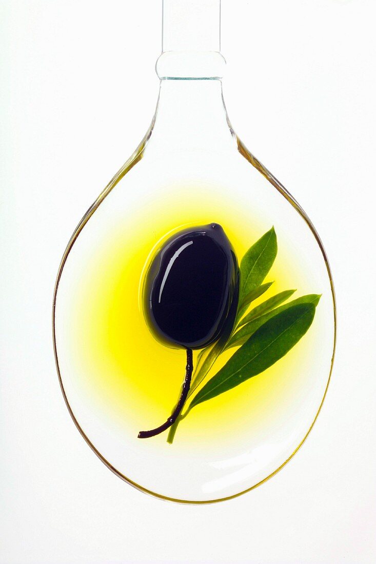 Schwarze Olive auf Löffel in Olivenöl
