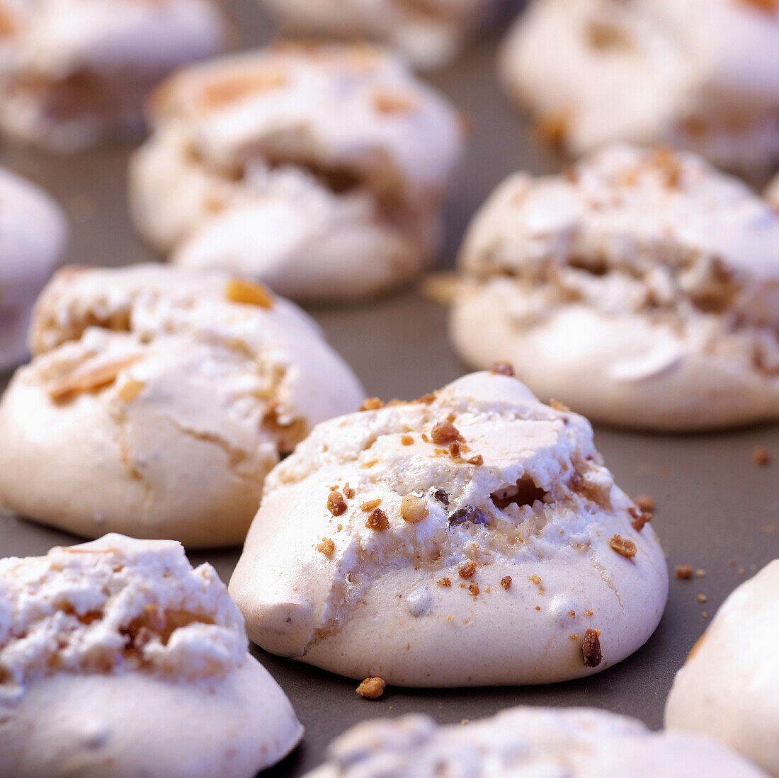 Meringues with crushed hazelnuts on baking tray