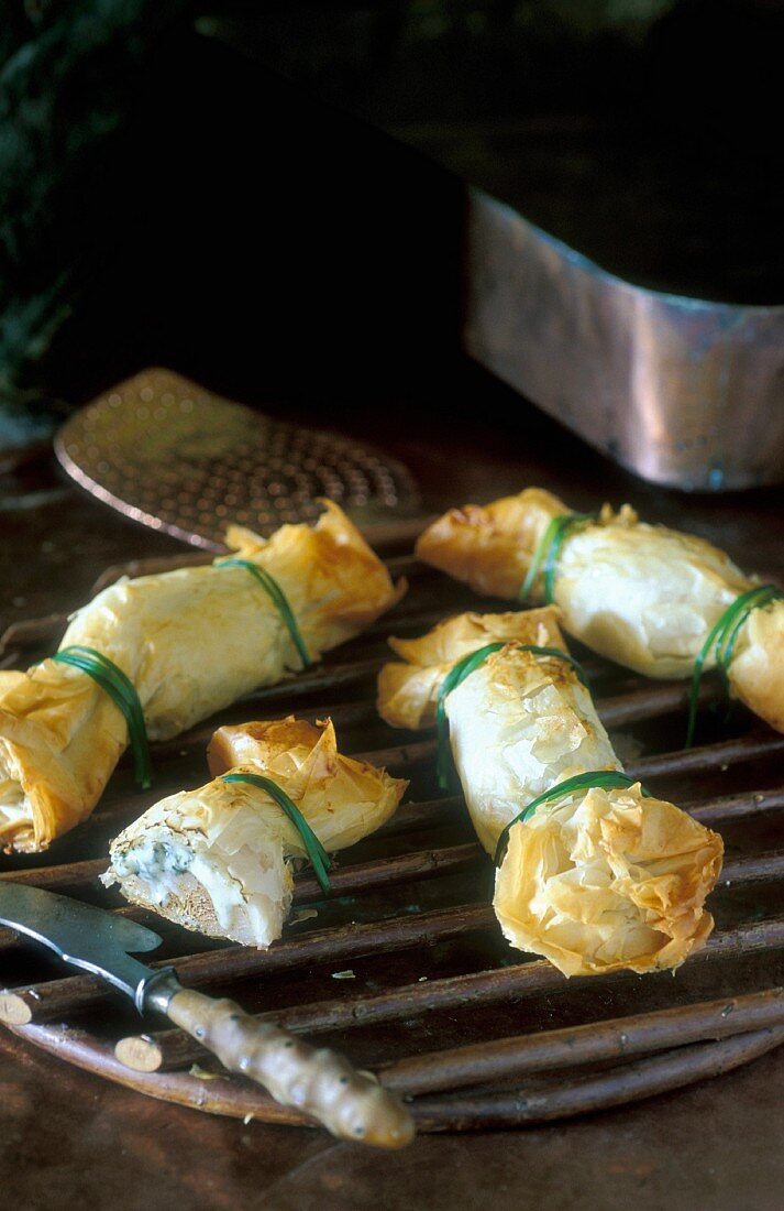 Mini pastry rolls filled with goat's cheese and peats tied with chives