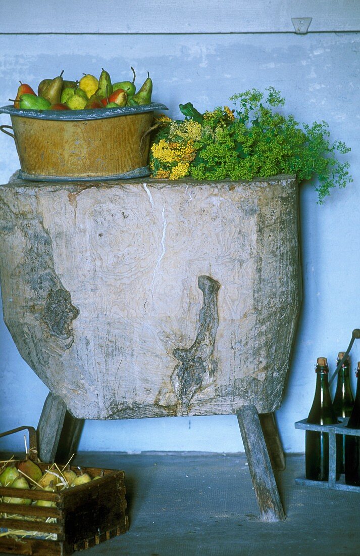 Birnen in einer Schale auf rustikalem Holzblock, daneben ein Träger mit Apfelweinflaschen