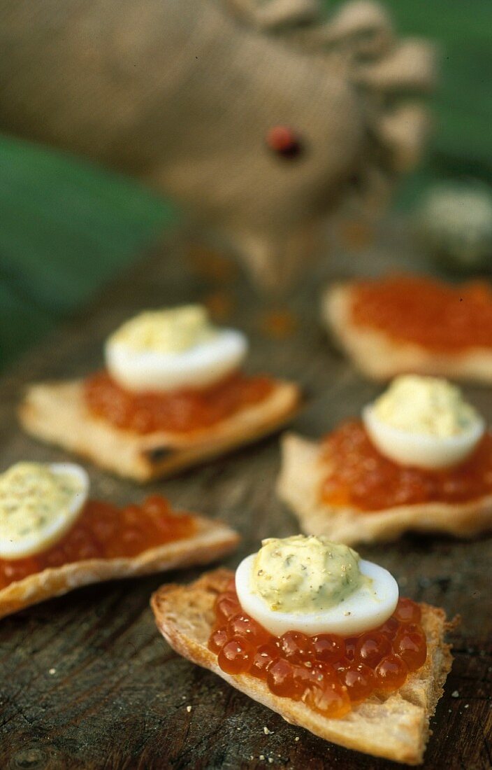 Crostini topped with salmon caviar, quail's eggs and herb mayonnaise