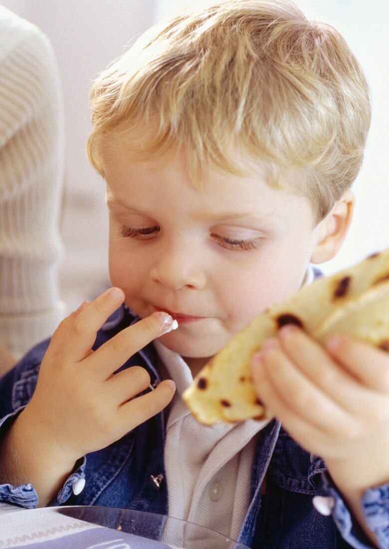 A little boy eating a crêpe